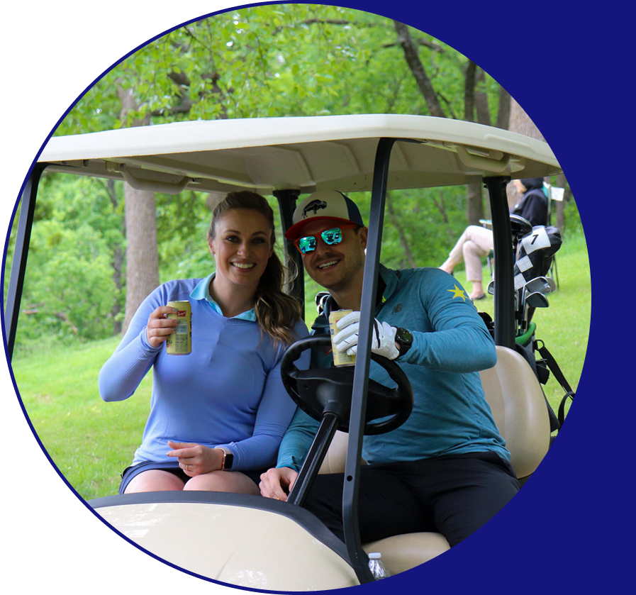 An image of two people smiling in a golf cart